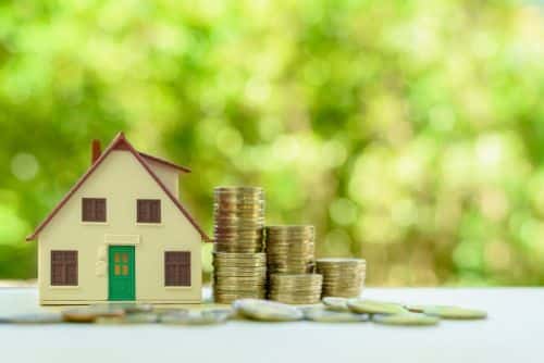 Small home model with green door and stacks of rising coins. Visual concept for a blog discussing Nevada probate laws and question s about the the Nevada Probate process.