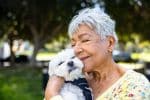 a senior woman hugging her small white dog - estate planning for pets concept