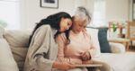 Mother and daughter sitting on couch are mourning the passing of a loved one. Visual concept for an estate planning blog discussing what to do after a loved one dies.